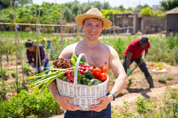 Happy farmer with basket of vegetables in the garden