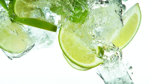 Super slow motion of lime slices falling into water with ice cubes on white. Filmed on high speed cinema camera, 1000 fps.