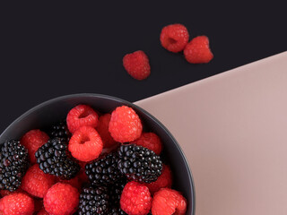 Blackberries and raspberries in a black bowl. Black and light pink background.