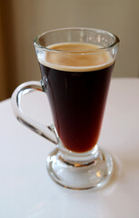 Vertical Image of Hot Black Coffee in a Transparent Glass Isolated on White Table