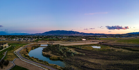 Panoramic view of a river flowing under a highway with a city and mountains inn the distance