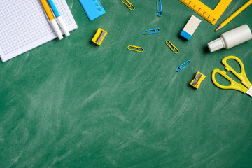 Flat lay school stationery on a green chalkboard background. Back to school education concept. Top...