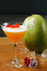 Caipirinha brazilian typical coktail, exotic tropical flavor coconut water blend mango fruit juice syrup with flower petals, served on fresh ice cold glass. Beautiful colorful drink on close up view.