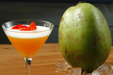 Caipirinha brazilian typical coktail, exotic tropical flavor coconut water blend mango fruit juice syrup with flower petals, served on fresh ice cold glass. Beautiful colorful drink on close up view.