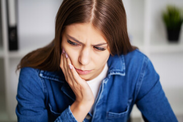 Exhausted woman in the office suffering from severe toothache