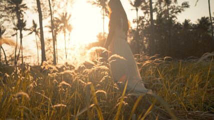 Sunset landscape with woman in dress stands among grass field © Artur
