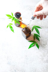 Woman holding a dropper with a bottle of hemp oil in a pipette, natural herbs.