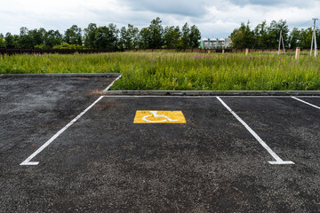 a yellow sign on the asphalt shows a Parking place for people with disabilities, for the disabled, a road sign, markings on the road