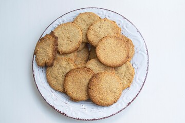 Composition of homemade macaroons in a light clay plate, on a light background. Top view