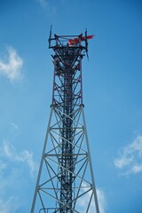 Communication tower on a background of blue sky. A weather vane at the very top indicates the direction of the wind. The image of freedom.