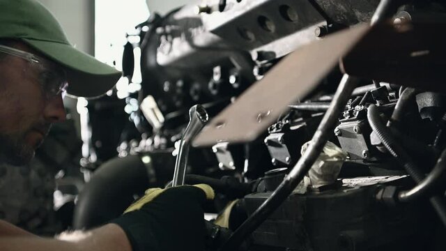 Repair Service Male Technician Working On Bus Engine In Mechanic Garage Using Wrenches To Tighten Bolts Of Mechanism. 
