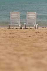 Deck chair in the sand on the shore. Relax, relaxation on the beach. Blue water in the ocean sea.