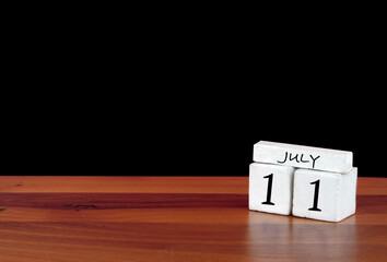 11 July calendar month. 11 days of the month. Reflected calendar on wooden floor with black background