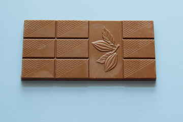 Milk chocolate isolated on blue background from top view. Close up a chocolate bar isolated on blue background.