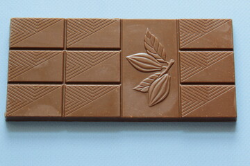 Milk chocolate isolated on blue background from top view. Close up a chocolate bar isolated on blue background.