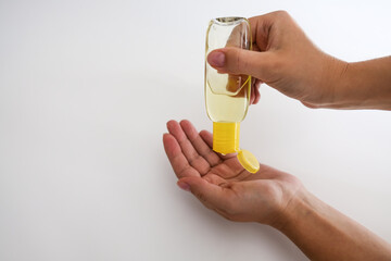 White female hands applying hand sanitizer at home. Woman taking care of herself in isolation during quarantine. Yellow antibacterial bottle with hygienic disinfectant gel. Coronavirus protection.