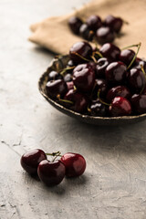 Ripe sweet cherry in ceramic bowl at concrete background