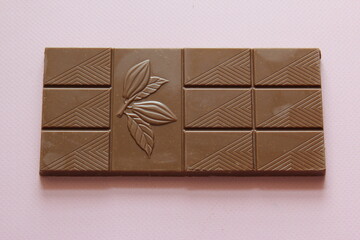 Milk chocolate isolated on pink background from top view. Close up a chocolate bar isolated on pink background.