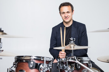 Young drummer behind drum set and plays the drums isolated on white background