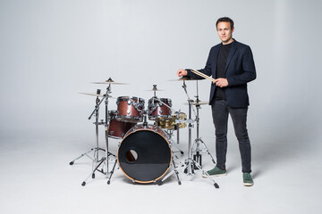 Young man standing on drum set isolated on white background