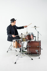 Young man drummer behind drum set and plays the drums in studio background