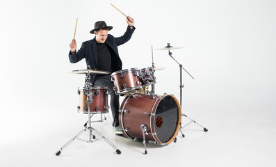 Young handsome man in hat and sunglasses playing drums isolated on white background