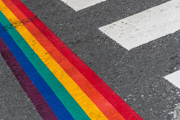 Paso de cebra de ciudad con bandera multicolor LGTBI por el día del orgullo por la igualdad