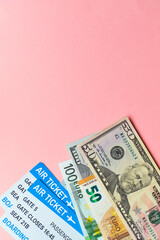 Travel concept with plane tickets and money on a pink background. vertical.