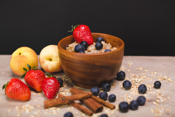 Still life - milk porridge with blueberries, strawberries, peaches and cinnamon sticks. Still life in photography. Photos of food. Oatmeal porridge In bowl