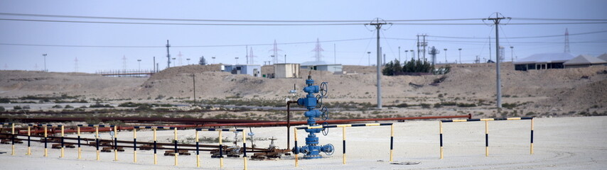 Blauer Druckmesser an einer Ölleitung im Wüstensand