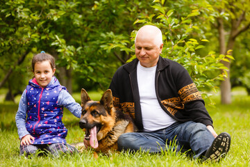 Portrait of small girl with senior grandfather in the backyard garden, standing.