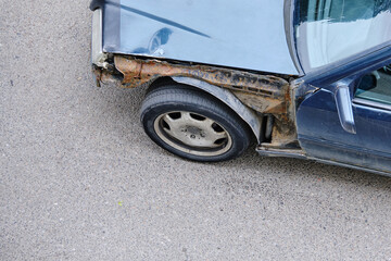 Naklejka premium Old abandoned car on the street without a body element with rust