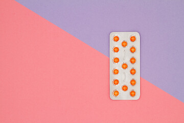 Top view of orange pills in blister on a colored background. Healthcare concept