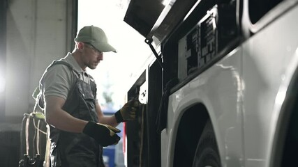 Male Repairman Checking Electrical Wiring And Connections In Large Commercial Bus. 