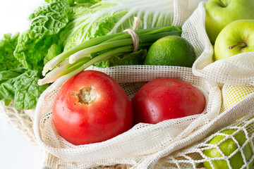 Plastic free. Healthy food. Fresh vegetables and fruits in eco-friendly reusable cotton bags on white background.