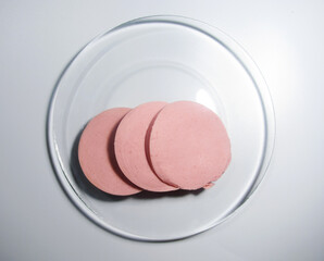 sliced pieces of cooked sausage on a transparent plate. The view from the top.