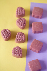 Chocolate candies on a purple and yellow background. Place for photo. Advertising photo.
