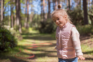 Cute adorable little caucasian child girl enjoy standing in forest during walk .Dreaming and feel free. Freedom lifestyle.
