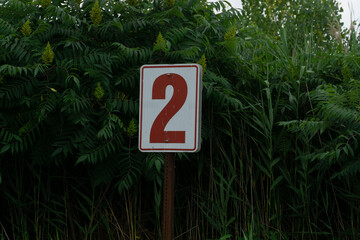 Number Two, 2 Sign in front of trees and plants in public park