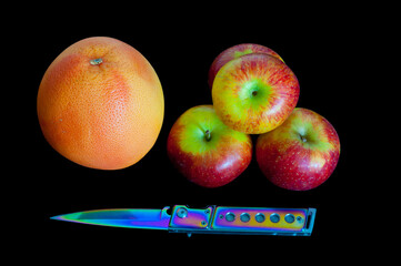 Grapefruit, 4 apples and a knife on a black background.