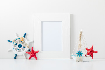 Summer composition. Travel concept. White frame mockup in interior with sea elements on white wall...