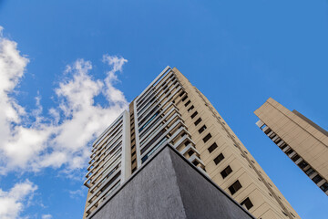 Pr&eacute;dio visto de baixo pra cima, com c&eacute;u azul com nuvens.