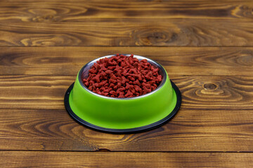Dry food for cat or dog in bowl on wooden background. Pet food on wood surface
