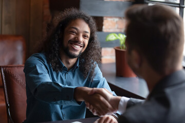 Mixed-race successful applicant express gratitude shake hands with employer got hired at company...