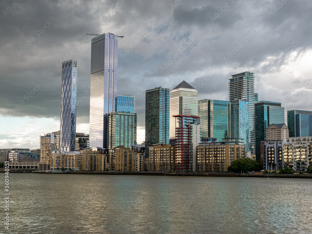 Wall mural Tall buildings accros the river Thames in the city area of London, Canary Wharf financial district of England