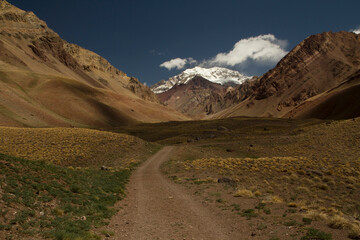 Seven summits. Mountaineering. Path across the valley and golden meadow, leading into mountain Aconcagua, highest peak in America. 