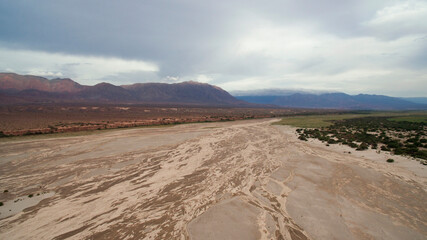 Natural textures. Aerial view of the arid desert, sand, dunes and mountains under a cloudy sky. 