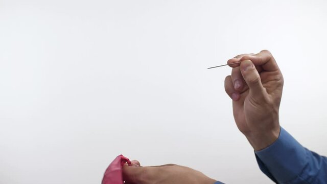 Man pierces a balloon with a needle