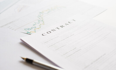 Contract paper and pen on white desk background. Focus on title Contract. Defocused pencil.