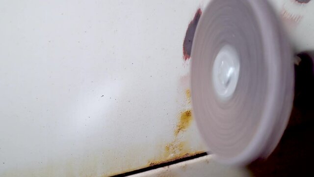Mechanic grind old paint and rust from car body using drill with scotch brite circle in auto repair shop. Car body repair
